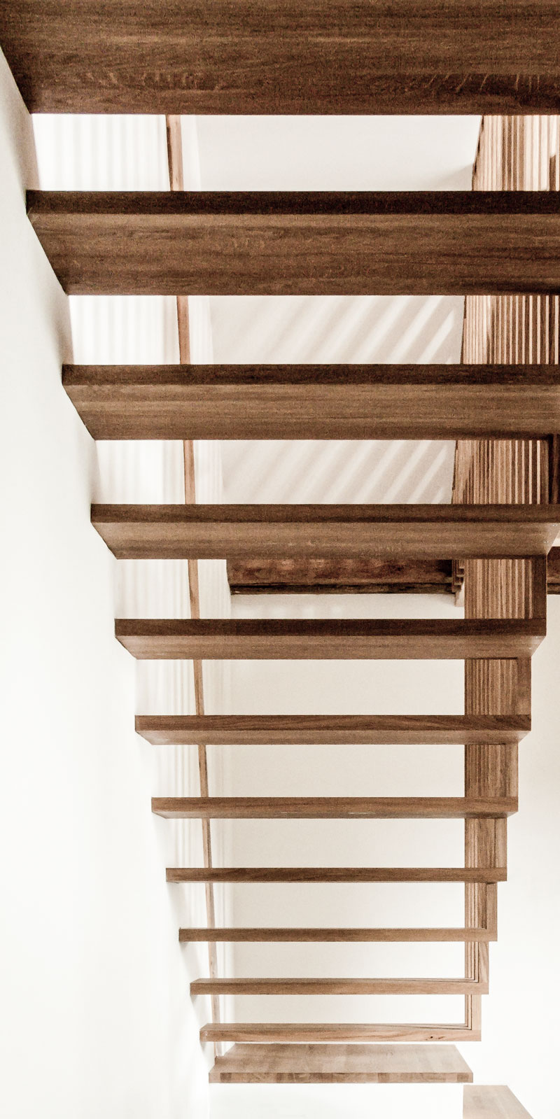 die-stufen-der-treppe-aus-geoeltem-eichenholz-sind-einseitig-in-der-wand-befestigt-und-auf-der-anderen-seite-aufgehaengt