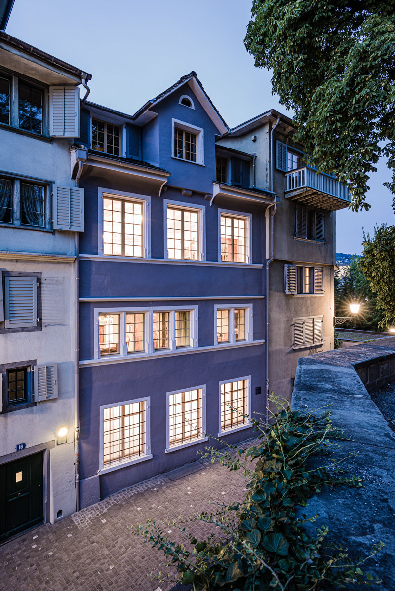 sued-fassade-des-altstadthauses-zum-schuetz-beim-lindenhof-in-zuerich-am-abend-mit-hell-erleuchteten-fenstern