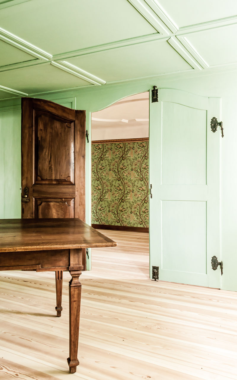 blick-vom-gruenen-salon-durch-die-doppel-fluegeltuer-zum-salon-daneben-der-eine-stuckdecke-und-floral-gemusterte-tapete-hat