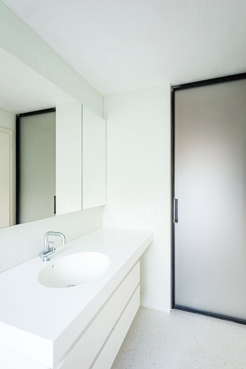 modernes-minimalistisches-bad-mit-weissem-waschtisch-corian-spezial-elliptischem-waschbecken-spiegel-und-metall-mattglastuer