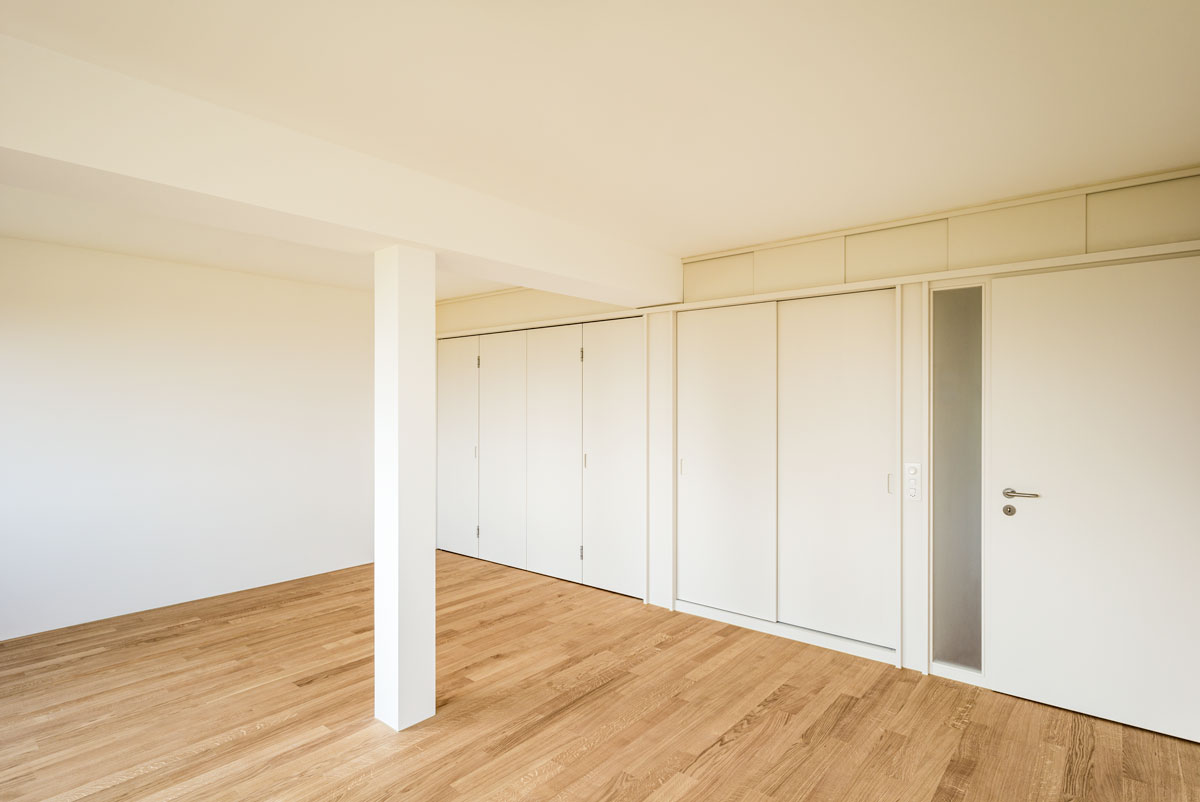 grosses-zimmer-mit-parkett-schiffboden-eiche-geoelt-hellen-einbaumoebeln-und-faltwand-geschlossen