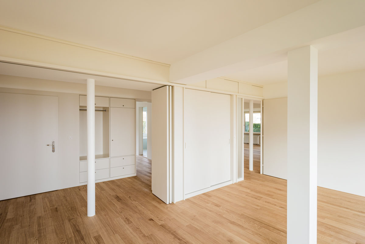 grosses-zimmer-mit-stuetzen-und-offener-faltwand-und-blick-zum-entree-mit-garderobe-und-richtung-bad-und-esszimmer