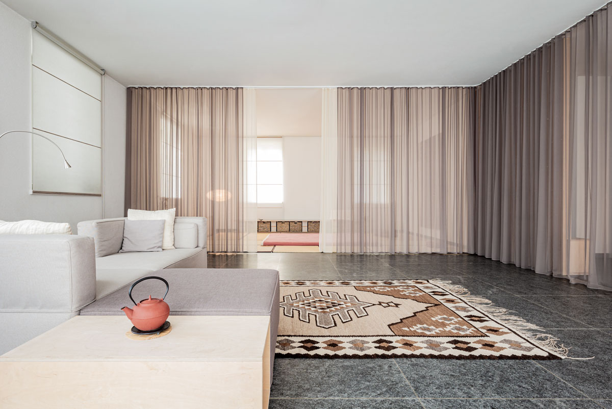 ein-doppelt-gefuehrter-vorhang-trennt-die-sitzguppe-vom-bereich-mit-dem-shiatsu-futon-und-dem-eingangsbereich