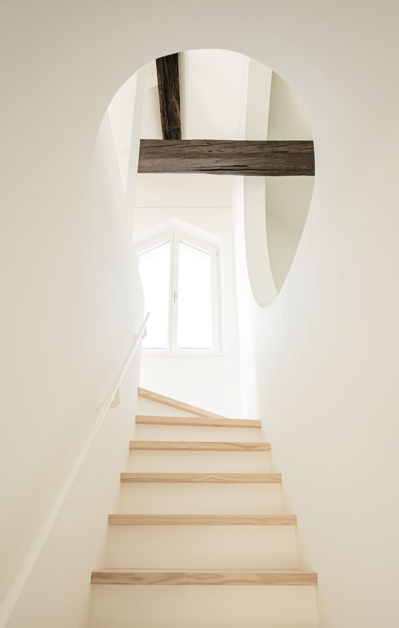 treppe-zur-galerie-mit-historischen-balken-und-tonnen-gewoelbe-gips-und-fliessendem-uebergang-zur-grossen-runden-oeffnung