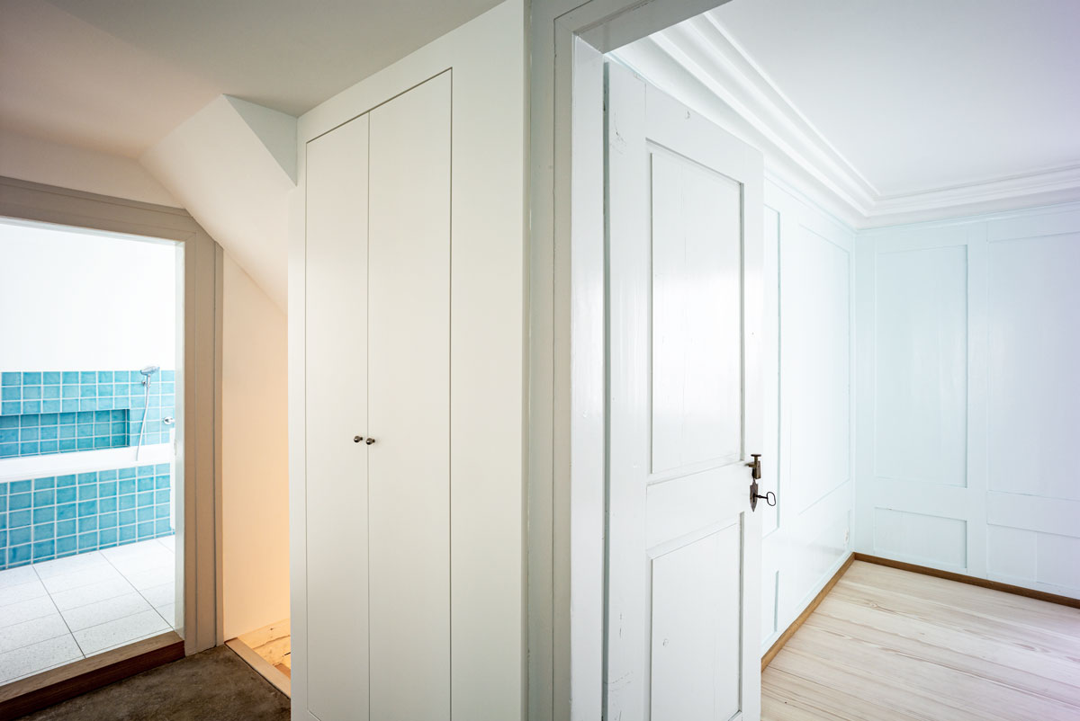 vorraum-zum-bad-und-schlafzimmer-mit-hellgrauer-tuere-und-neuem-einbauschrank-sowie-restauriertem-historischem-sandsteinboden