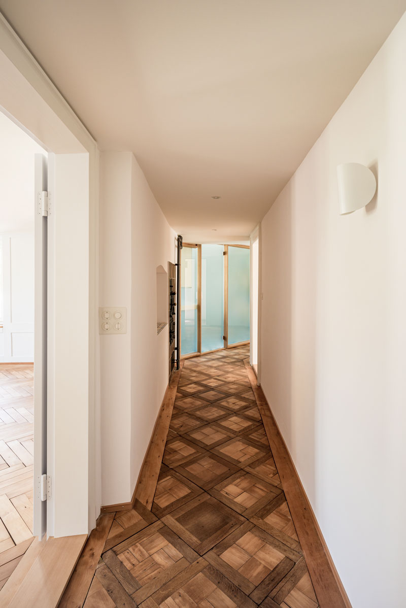 gang-mit-historischem-tafelparkett-und-moderner-neuer-mattglas-wand