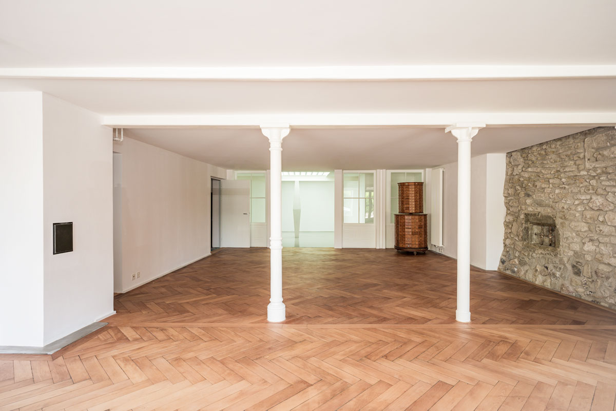 grosser-ladenraum-mit-fischgrat-parkett-eiche-gussstuetzen-aus-der-zeit-um-1900-und-freigelegter-bruchstein-wand