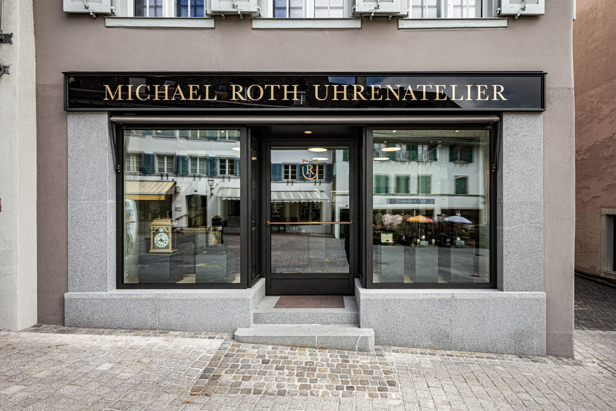 schaufenster-und-eingang-des-uhrenateliers-michael-roth-mit-stahlrahmen-sowie-sockel-und-seitenteilen-aus-guber-quarzstein