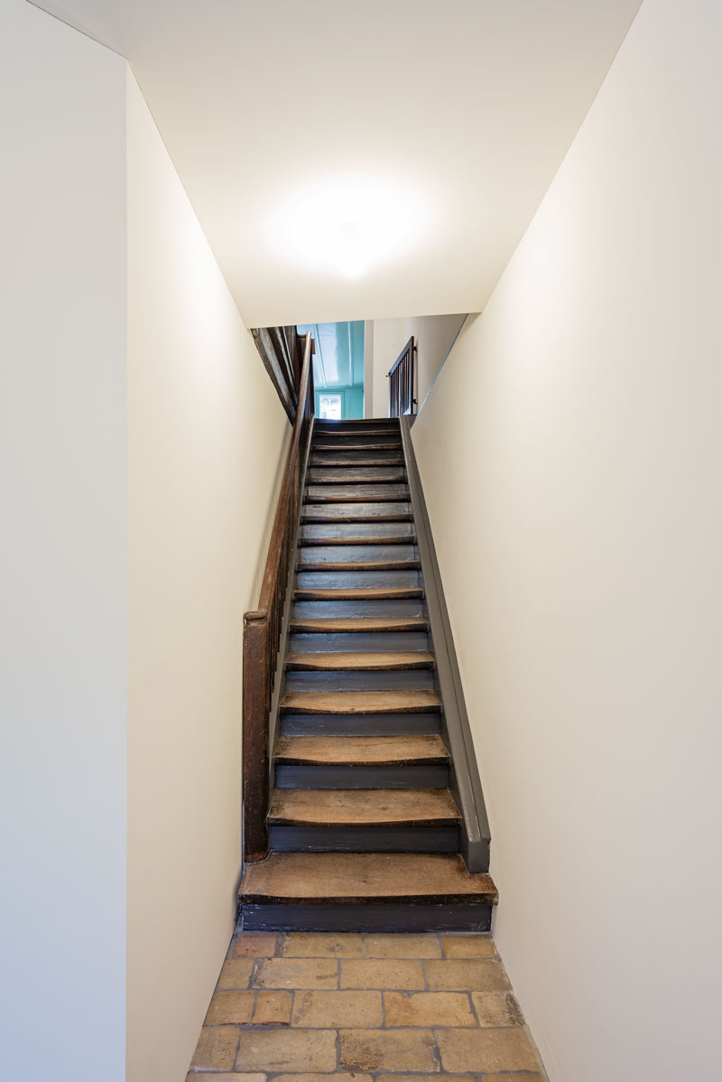 entree-mit-historischer-treppe-und-tonplatten-boden-und-neuen-modernen-wand-und-decken-ergaenzungen-in-gips
