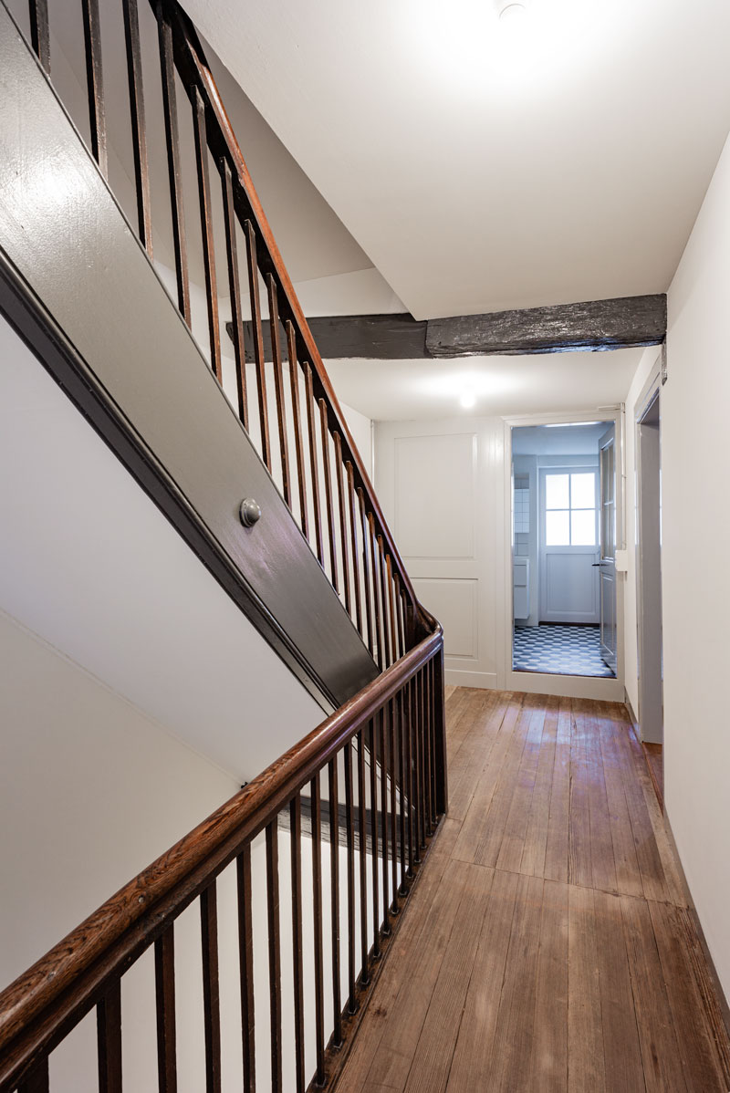 gang-mit-historischer-treppe-mit-dunkelbraunen-holz-staketen-und-wangen-in-oelfarbe-anthrazit